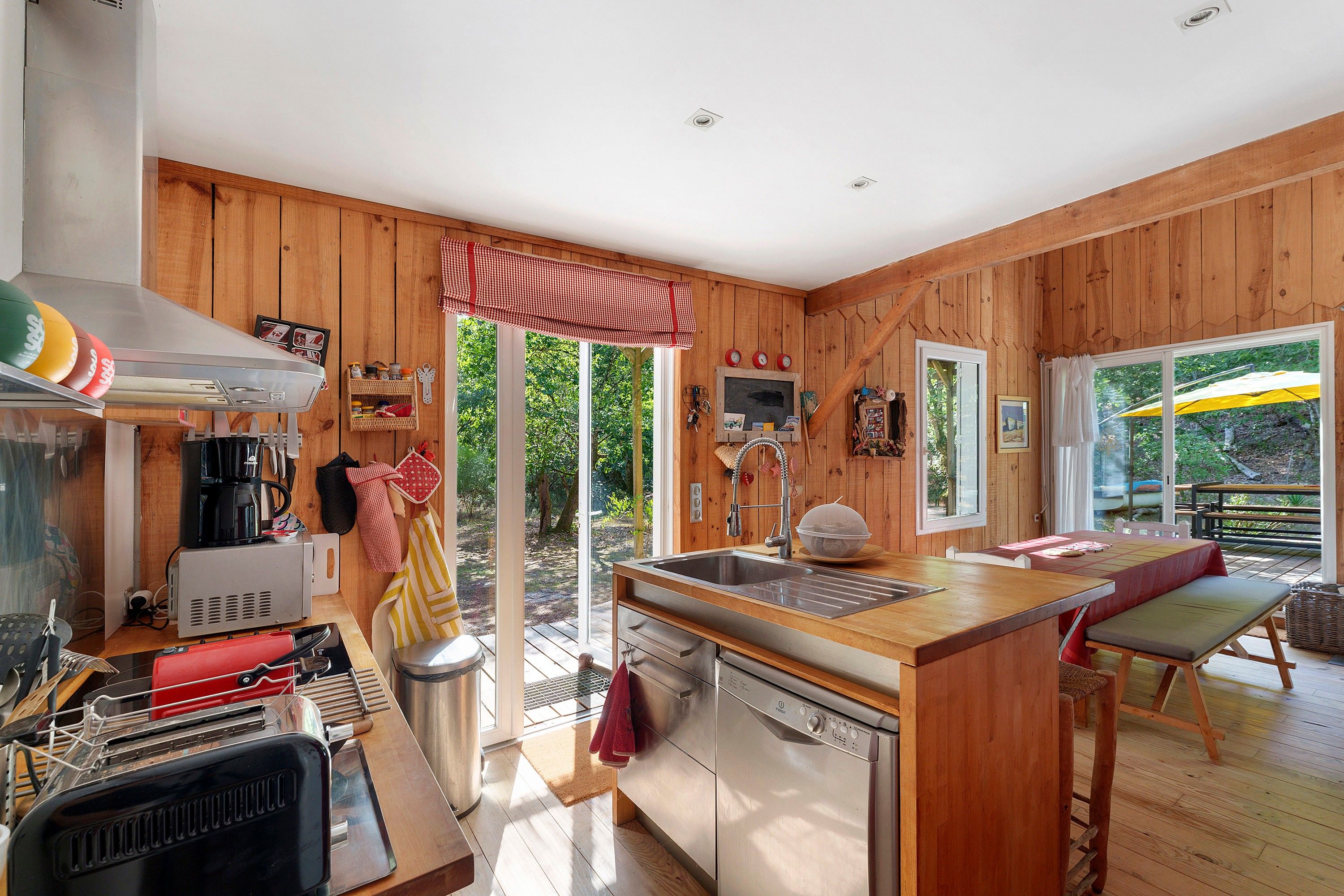 Un interior de madera con una zona de cocina, que incluye un lavamanos, estufa y varios electrodomésticos.