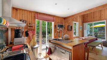 Un interior de madera con una zona de cocina, que incluye un lavamanos, estufa y varios electrodomésticos.