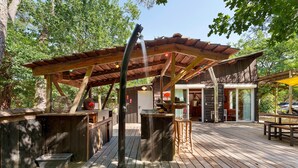 Una terraza de madera con pérgola, mobiliario exterior y una fuente de agua.