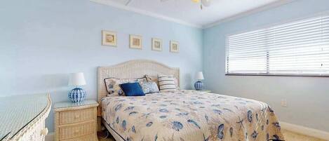 A bedroom with a bed, nightstands, a ceiling fan, and a window with blinds.