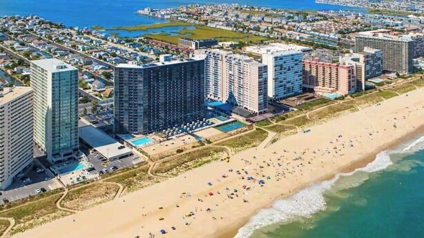Un paisaje urbano costero con edificios altos, una playa y una zona de piscina.