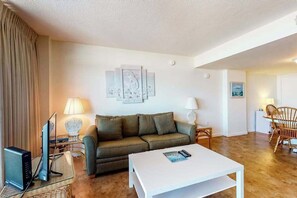 Ein Wohnzimmer mit einer Couch, einem Couchtisch, einem Fernseher und einer Lampe.