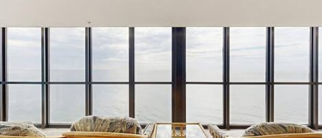 A room with large windows, wicker furniture, and a glass table.