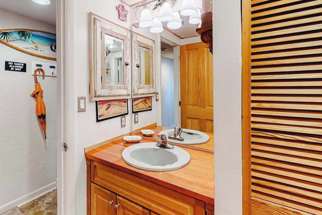Een badkamer met twee wastafels, een houten wastafelmeubel, spiegels en een handdoekhouder.
