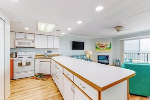 A compact kitchen with white cabinets, a microwave, stove, and a large island. - Direct oceanfront top floor condo w/outdoor pool, balcony, easy beach access (Ocean City)