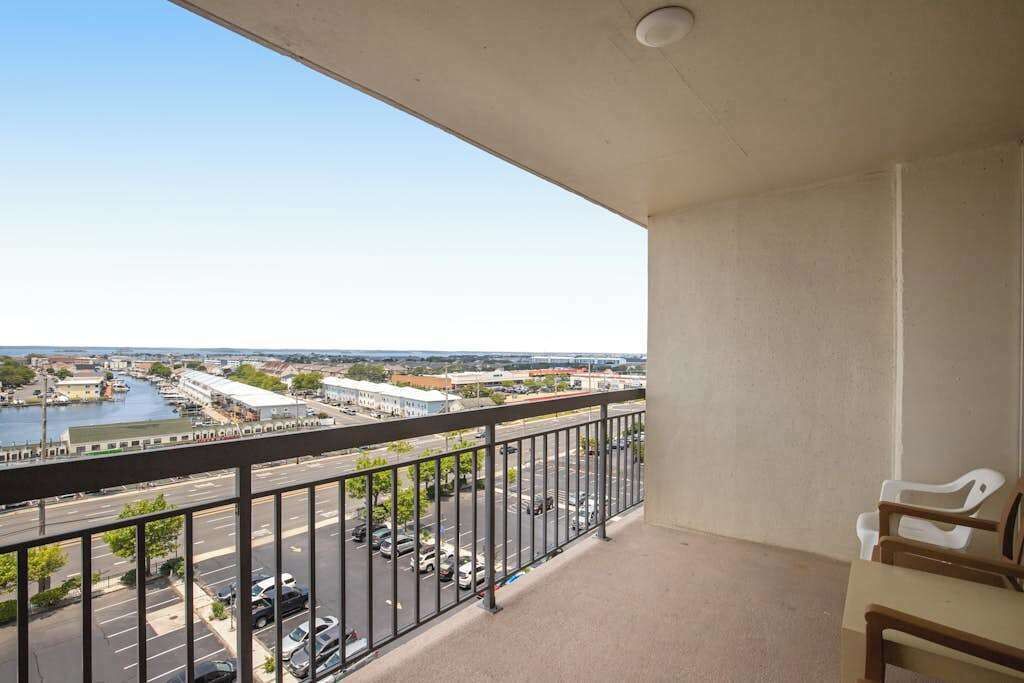 A balcony with a view of a marina and cityscape, a railing, and a chair.