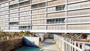 Un edificio de varios pisos con balcones, una terraza de madera y una entrada con portón.