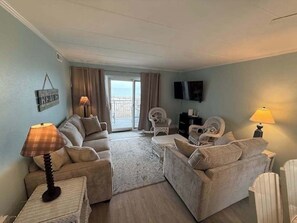 A living room with a sofa, armchairs, a coffee table, a TV, and a balcony view. - Diamond Beach 204 (Ocean City)