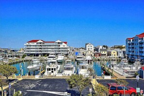 Un puerto deportivo con barcos amarrados, un edificio grande con techo rojo y un coche rojo estacionado en primer plano.