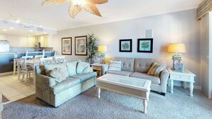 A spacious living room with a ceiling fan, a dining area, and a kitchen in the background. - Emerson Towers 301 (Ocean City)