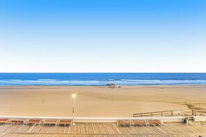 Blick auf einen Strand mit einer Holzterrasse und Stühlen.
