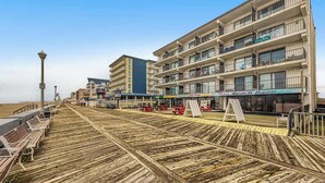Een vogelvlucht van een houten looppad met banken, een strand en een meerhoog gebouw met balkons.