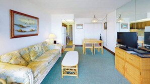 Een woonkamer met een bank, een eettafel, een televisie en een keukenhoek.
