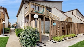 A residential building with a wooden deck, a covered outdoor area, and a gated entrance. - Club Ocean Villa II 117 (Ocean City)