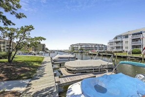 A marina with docked boats, a wooden walkway, and multi-story buildings in the background. - Club Ocean Villa II 117 (Ocean City)