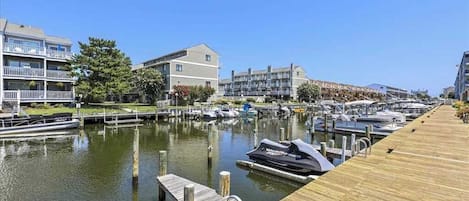A marina with docked boats, wooden walkways, and residential buildings.