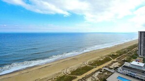 Blick auf einen Strand mit Hotel, Meer und blauem Himmel.