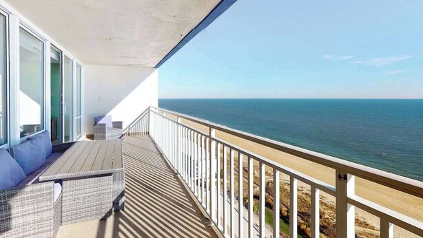 Ein Balkon mit Blick auf das Meer, einer Holzterrasse und einem weißen Geländer.