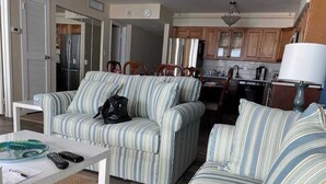 Ein Wohnzimmer mit gestreiften Sofas, einem Couchtisch und einer Küchenzeile im Hintergrund.