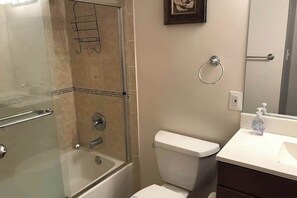 Ein Badezimmer mit einer Duschkabine, Toilette, Waschbecken mit Seifenspender und Handtuchhalter.