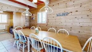 Un interior de madera con una mesa de comedor y sillas, un ventilador de techo y un letrero en la pared.