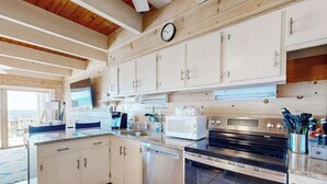 Una cocina moderna con armarios blancos, electrodomésticos de acero inoxidable y un reloj en la pared.
