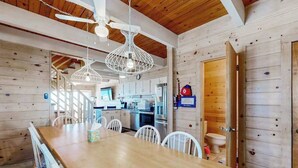 Un interior de madera con una mesa de comedor, sillas, ventiladores de techo y una zona de cocina.