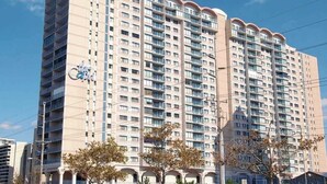 A high-rise building with multiple balconies, a prominent clock, and a clear sky. - Unique Condo w/Side Views of the Beach, Private Balcony, Shared Pools, Gym, A/C (Ocean City)