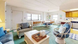 Una sala de estar con sofá, sillón, mesa de centro y comedor con sillas y mesa.