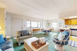Ein Wohnzimmer mit einer Couch, einem Sessel, einem Couchtisch sowie einem Essbereich mit Stühlen und Tisch.