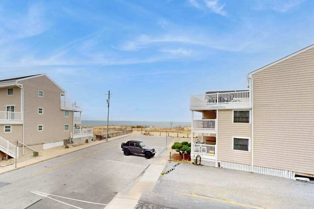 A coastal building with a balcony, a parking lot, and a beach view.