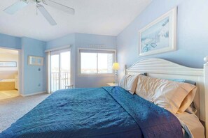 A bedroom with a bed, a ceiling fan, a window, and a door. - Charming Bayfront Condo Close to the Beach w/Shared Pool, Free WiFi, Private W/D (Ocean City)