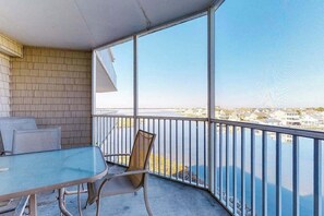 A balcony with a glass table and chairs, a view of a body of water, and a brick wall. - Captiva Bay 311 (Ocean City)