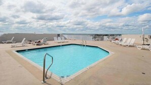 Ein Pool auf dem Dach mit Liegestühlen und blauem Himmel.