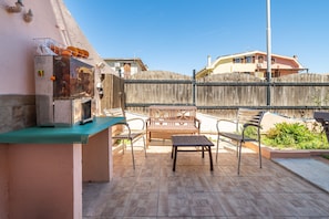 Patio esterno con barbecue, posti a sedere e vista sulle case vicine.