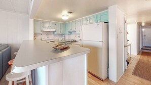 Een moderne keuken met witte kasten, een centraal eiland en een koelkast.