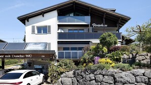 Un edificio de varios pisos con balcones, un cartel que dice 'Fürsthaus' y un coche estacionado adelante.