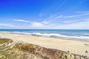 Ein Strand mit Zaun, Sanddünen und dem Meer.