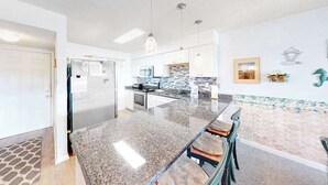 Eine moderne Küche mit Granit-Arbeitsplatten, Edelstahlgeräten und Pendelleuchten.