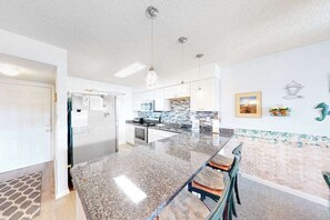 A modern kitchen with granite countertops, stainless steel appliances, and pendant lighting. - Blaire Isle 301 S (Ocean City)