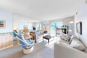 Uma sala de estar com sofá, poltrona, mesa de centro e televisão.