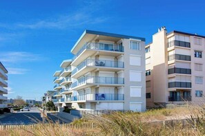 A multi-story residential building with balconies, a parking area, and a clear sky. - Blue Sea Colony 501 (Ocean City)