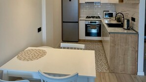 A modern kitchen with a central island, a built-in oven, and a microwave. - Cozy minimalistic apartment in Bagebi (T'bilisi)
