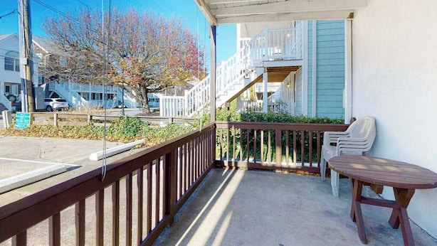 Un balcon avec une balustrade en bois, une table et deux chaises.