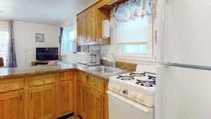 Une cuisine avec des meubles de rangement en bois, une cuisinière, un réfrigérateur, un four à micro-ondes et un évier.