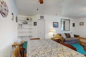 A room with a bed, a sofa, a table, and a chair. There is a clock on the wall and a door in the background. - Bell Harbour 2 (Ocean City)