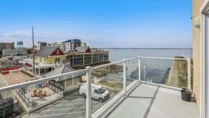 En balkong med utsikt över en småbåtshamn, en parkeringsplats och byggnader i bakgrunden.