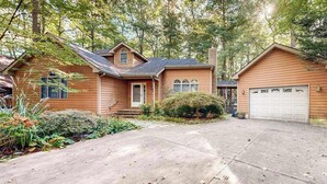 Une maison à deux étages avec un garage à l’avant, une allée et un jardin bien entretenu.
