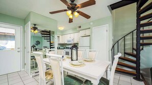 A dining area with a white table, green upholstered chairs, a ceiling fan, and a kitchen in the background. - Canal View Townhouse w/Private Deck, Washer/Dryer, & Private Balcony (Ocean City)
