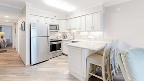 A modern kitchen with white cabinetry, stainless steel appliances, and a central island. - Marigot Beach 1206 (Ocean City)